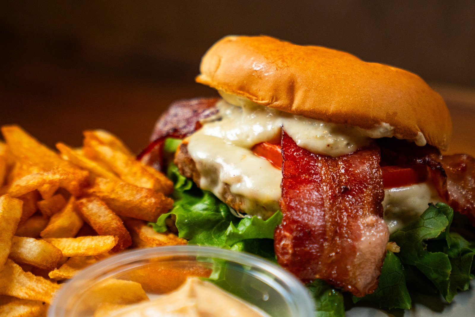 Bacon cheeseburger with lettuce and tomato served with fries at Bruges Belgian Bistro