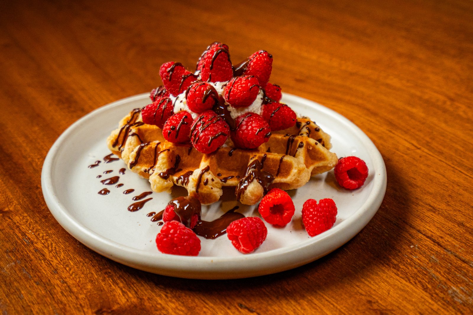 Liège waffle topped with raspberries and chocolate drizzle at Bruges Belgian Bistro